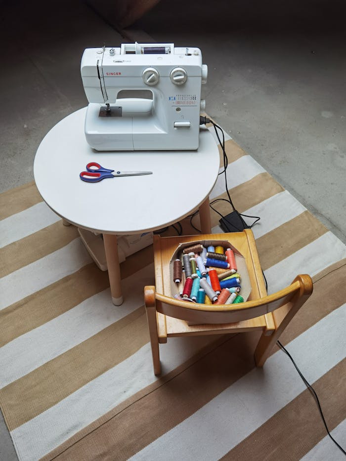 A sewing setup featuring a sewing machine, colorful threads, and scissors on a striped rug.